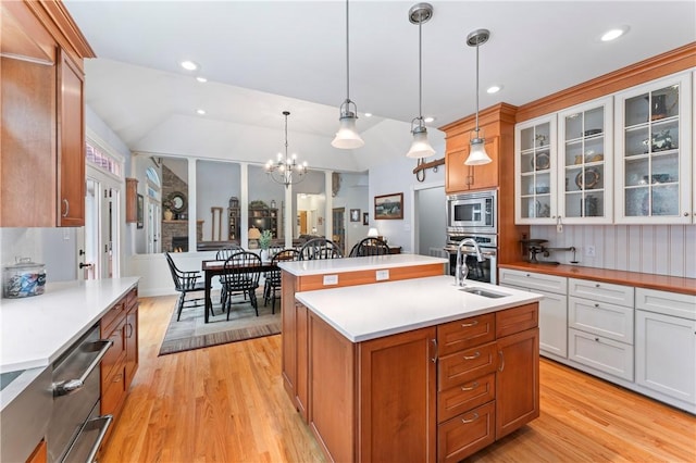 kitchen featuring stainless steel appliances, light countertops, a kitchen island with sink, and glass insert cabinets