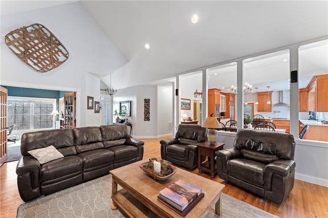 living room with a chandelier, baseboards, high vaulted ceiling, and light wood finished floors