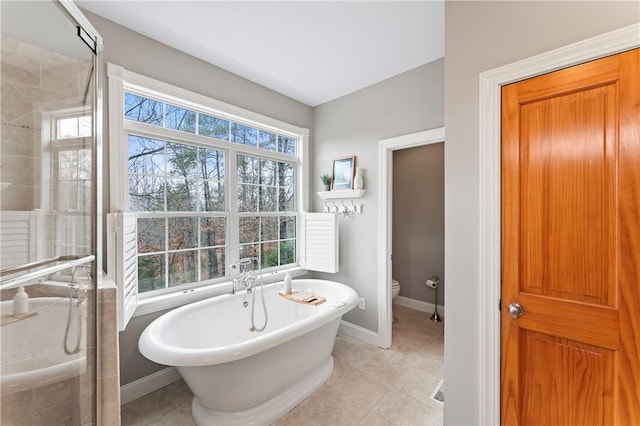 full bathroom with tile patterned flooring, a freestanding tub, a shower stall, and toilet