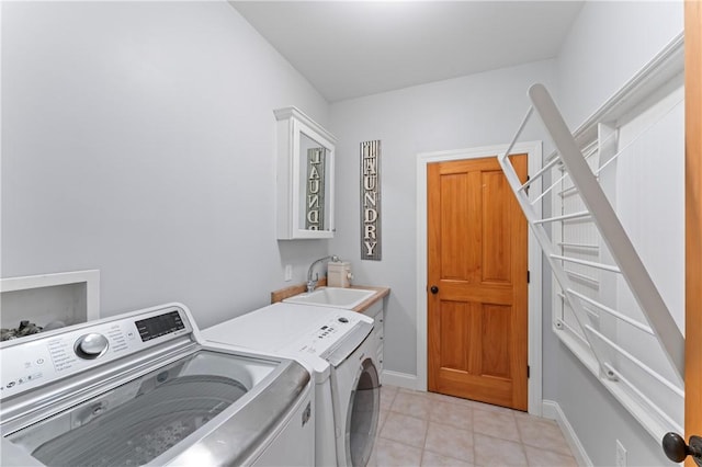 washroom with light tile patterned floors, cabinet space, a sink, separate washer and dryer, and baseboards