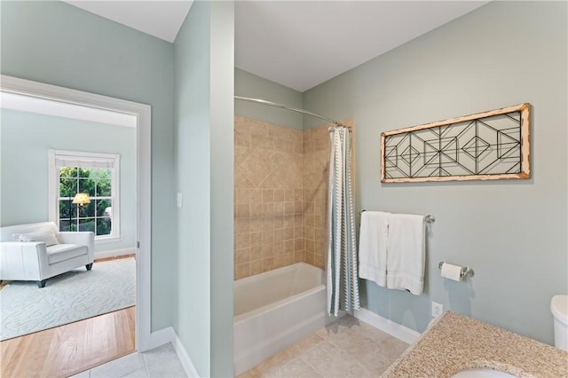 bathroom featuring baseboards, toilet, tile patterned flooring, shower / bathtub combination with curtain, and vanity