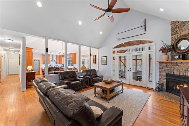 living area featuring french doors, a fireplace, light wood-style flooring, ceiling fan, and high vaulted ceiling