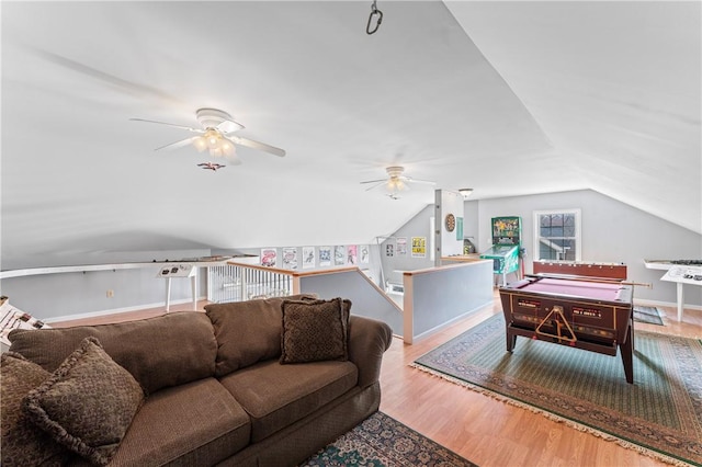 living area featuring lofted ceiling, ceiling fan, baseboards, and wood finished floors