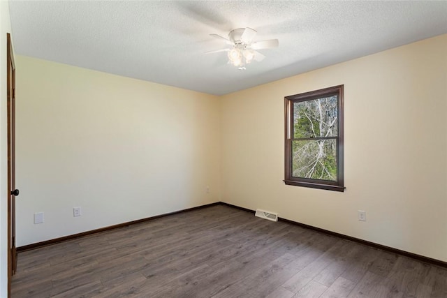 unfurnished room featuring dark wood-style floors, visible vents, a textured ceiling, and baseboards