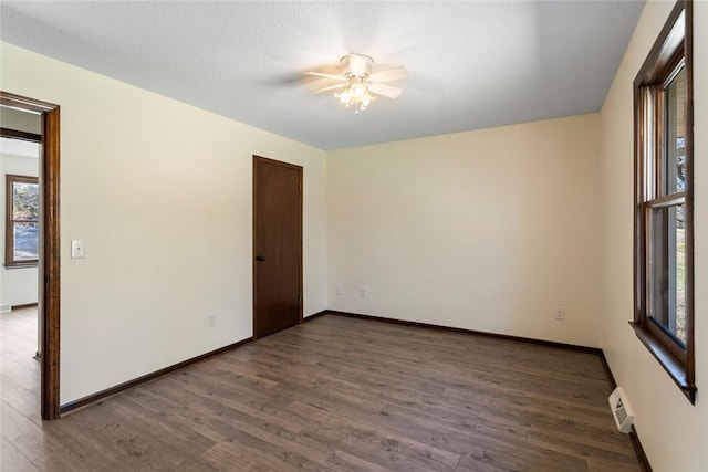 spare room featuring visible vents, a ceiling fan, a textured ceiling, wood finished floors, and baseboards