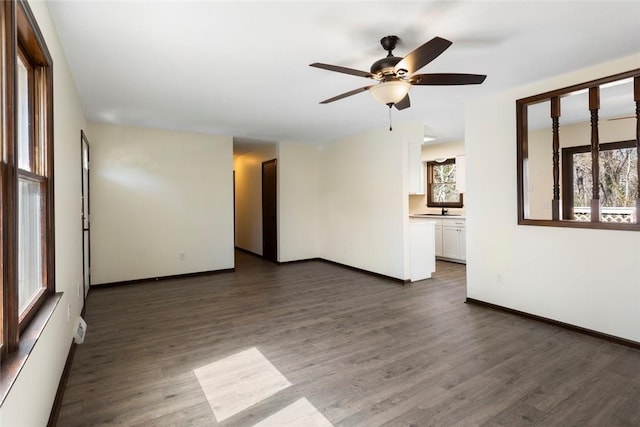 unfurnished room with a ceiling fan, baseboards, and dark wood-style flooring