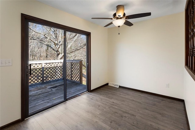 unfurnished room featuring baseboards, visible vents, and wood finished floors