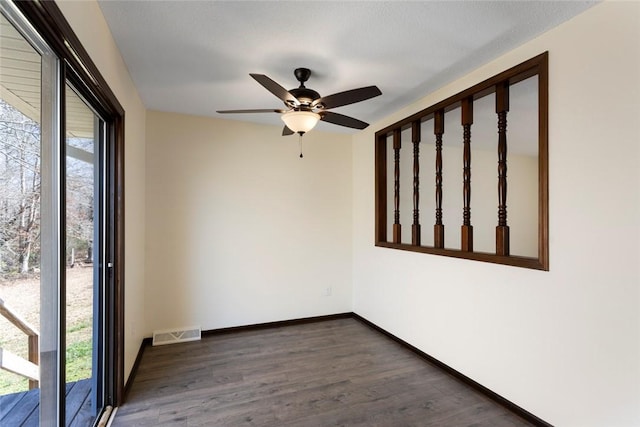 spare room featuring dark wood-type flooring, visible vents, plenty of natural light, and baseboards