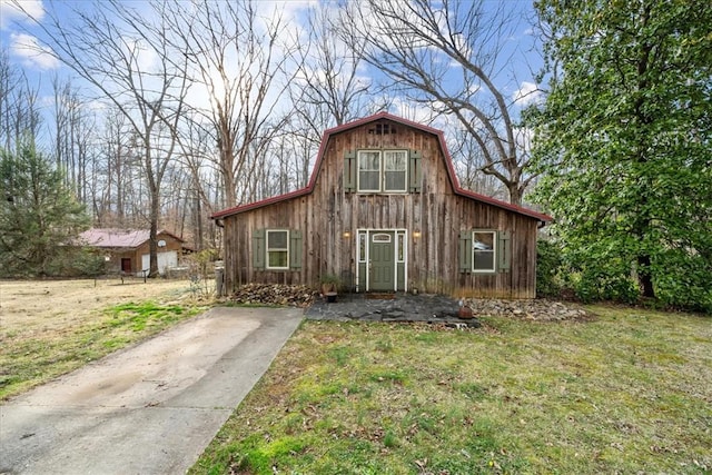 view of front of property featuring a front lawn, a gambrel roof, an outdoor structure, and a barn