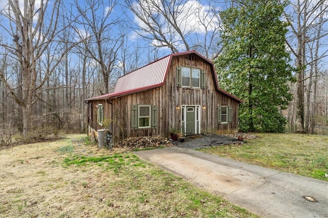 view of front facade with a gambrel roof, metal roof, a barn, an outdoor structure, and a front lawn