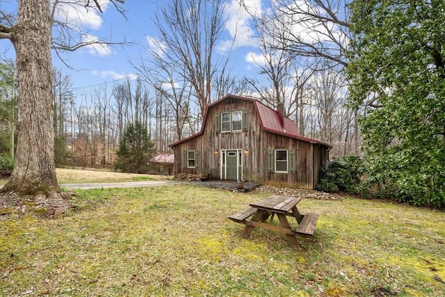 exterior space with metal roof, a lawn, a barn, and a gambrel roof