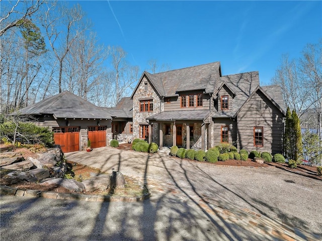 view of front of house featuring a garage, stone siding, and driveway