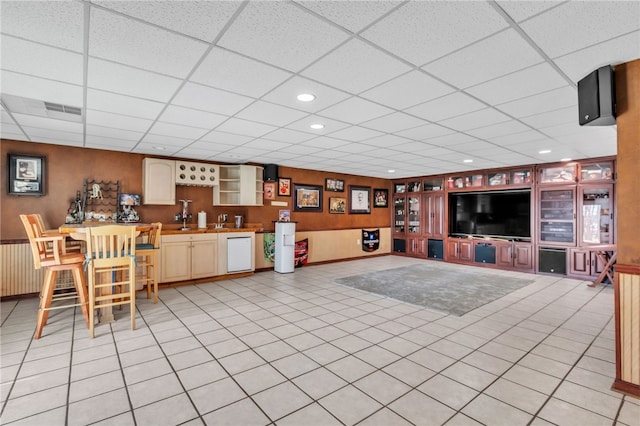 living room featuring built in features, visible vents, wooden walls, and light tile patterned flooring