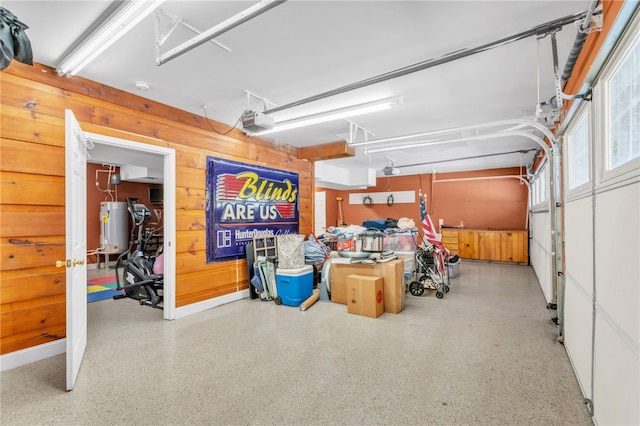 garage with wood walls, water heater, and a garage door opener