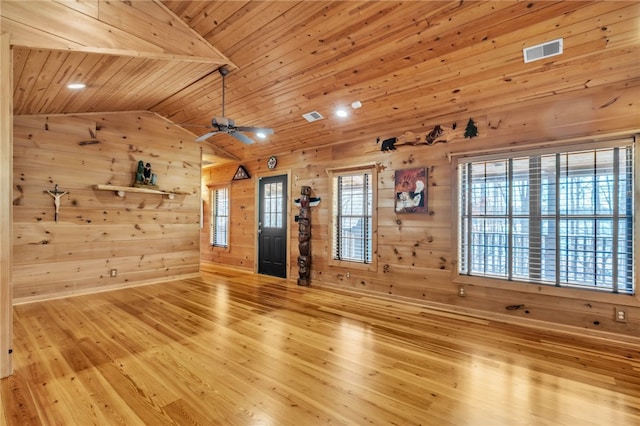 unfurnished living room featuring lofted ceiling, visible vents, wood walls, wood finished floors, and wooden ceiling