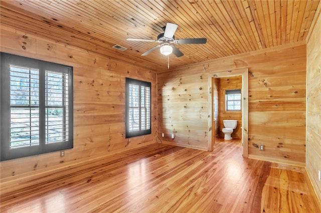 empty room with a wealth of natural light, wooden ceiling, wood finished floors, and visible vents