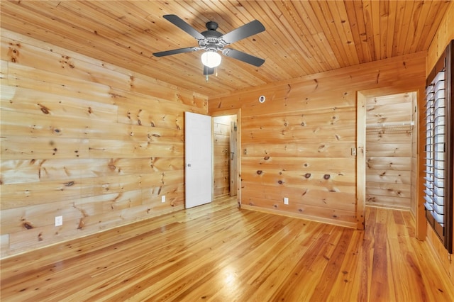 unfurnished room featuring light wood-type flooring, wood walls, wood ceiling, and a ceiling fan