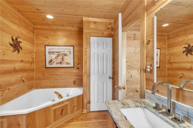 bathroom featuring a garden tub, wooden walls, wood finished floors, vanity, and wood ceiling