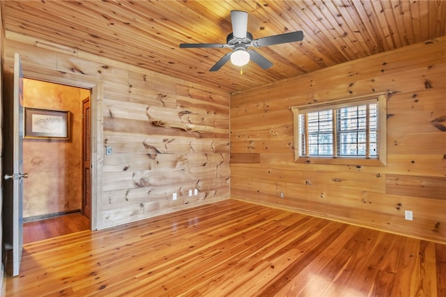 unfurnished room featuring wood ceiling, wood walls, hardwood / wood-style flooring, and a ceiling fan