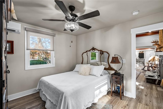 bedroom featuring a wall mounted air conditioner, wood finished floors, and baseboards