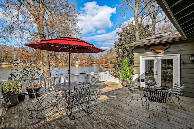 wooden deck with outdoor dining area and a water view