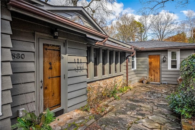 entrance to property featuring stone siding and a patio