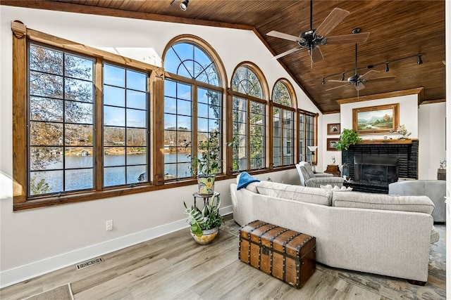 living room with a fireplace, a wealth of natural light, visible vents, wood ceiling, and wood finished floors