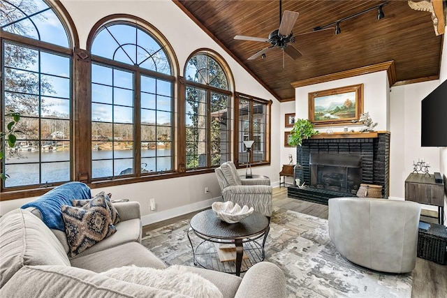 living area featuring baseboards, wood ceiling, wood finished floors, a water view, and a brick fireplace