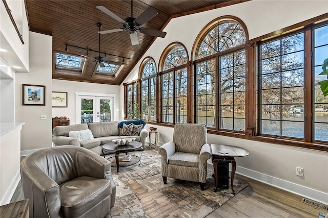 sunroom featuring wood ceiling, visible vents, a ceiling fan, french doors, and lofted ceiling with skylight