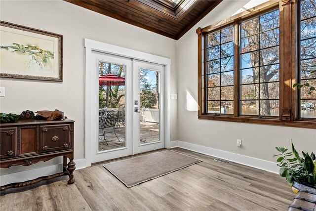 doorway with french doors, visible vents, lofted ceiling with skylight, wood finished floors, and baseboards