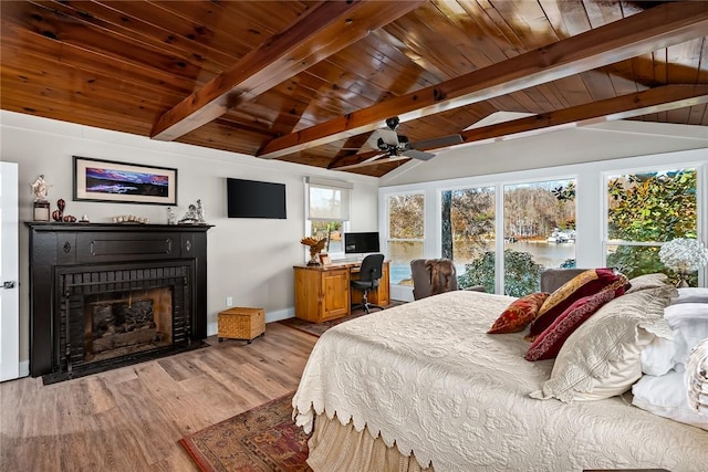 bedroom featuring lofted ceiling with beams, wooden ceiling, a fireplace with flush hearth, and wood finished floors