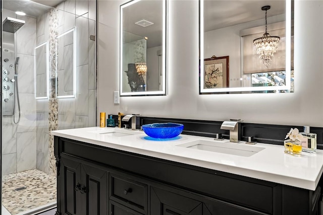 bathroom featuring double vanity, a notable chandelier, a shower stall, and a sink