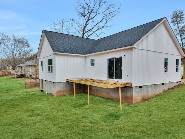 back of property with roof with shingles, crawl space, and a lawn