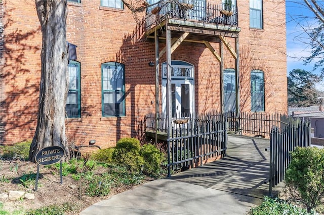 property entrance featuring brick siding and fence