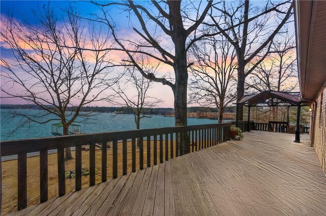 deck at dusk featuring a gazebo and a water view