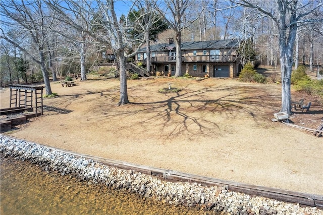 view of yard with a garage, driveway, stairway, and a wooden deck