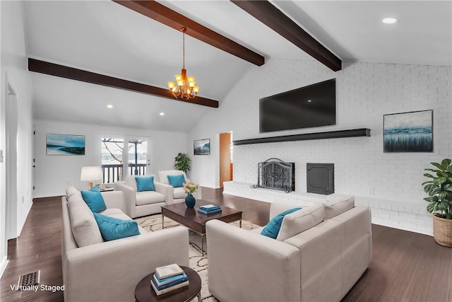 living room featuring lofted ceiling with beams, wood finished floors, an inviting chandelier, a brick fireplace, and recessed lighting