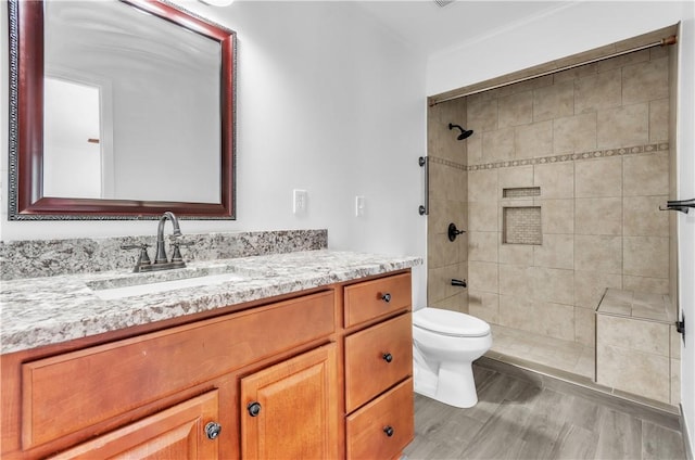 full bath featuring toilet, tiled shower, and vanity