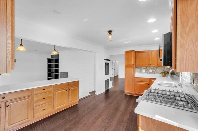 kitchen with light countertops, dark wood-type flooring, backsplash, and a sink