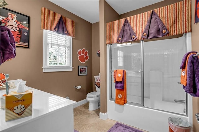 bathroom with toilet, baseboards, bath / shower combo with glass door, and tile patterned floors