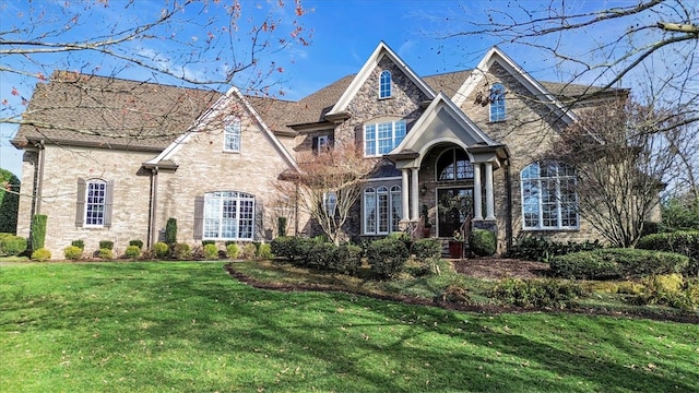 french country inspired facade with a front lawn and brick siding