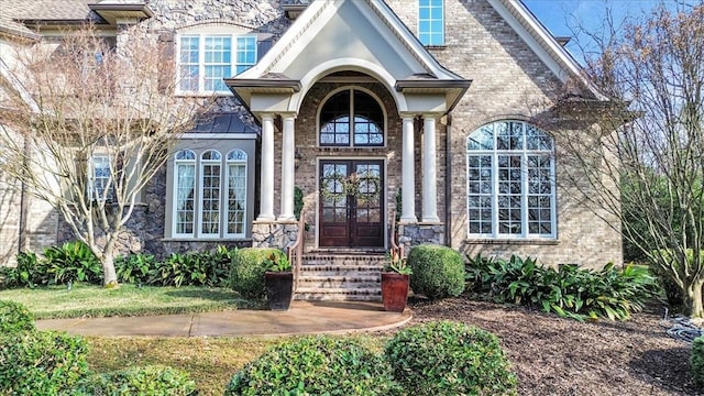 entrance to property with french doors, a standing seam roof, and brick siding