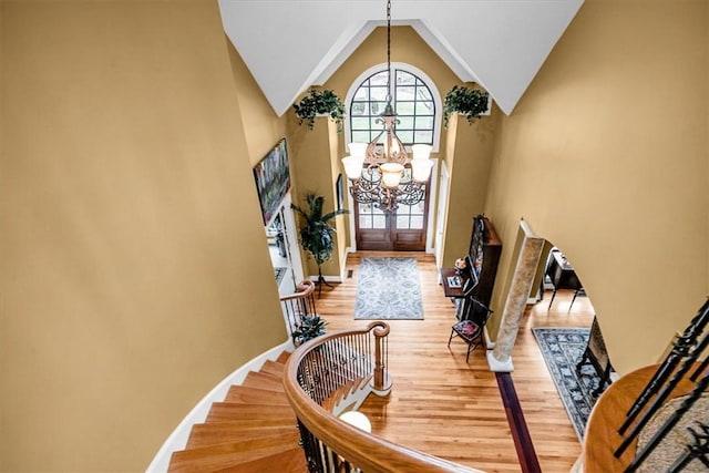 entrance foyer with high vaulted ceiling, baseboards, light wood-style floors, stairway, and an inviting chandelier