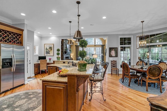 kitchen with a breakfast bar, light wood-style floors, ornamental molding, a chandelier, and stainless steel fridge with ice dispenser