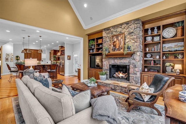 living area with baseboards, light wood-style flooring, crown molding, a stone fireplace, and high vaulted ceiling