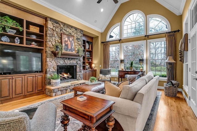 living room with plenty of natural light, a stone fireplace, ornamental molding, and light wood-type flooring