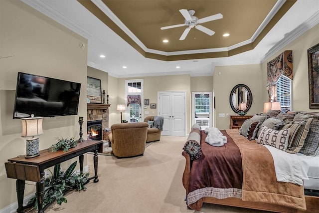 bedroom with ornamental molding, carpet, a raised ceiling, and a stone fireplace