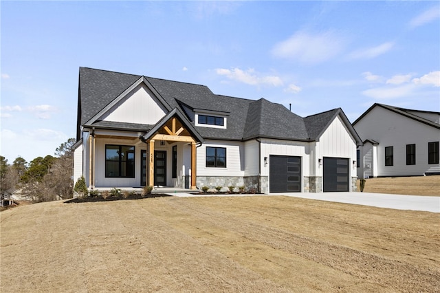 modern inspired farmhouse with a garage, a shingled roof, concrete driveway, stone siding, and board and batten siding