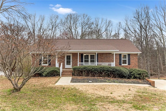 ranch-style home featuring roof with shingles, a front lawn, a porch, and brick siding