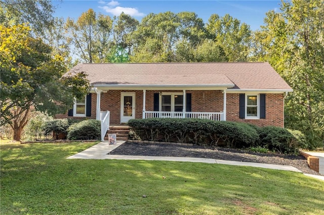 single story home featuring covered porch, brick siding, a front yard, and a shingled roof